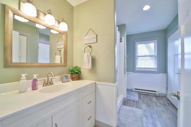 bathroom with vanity, a wainscoted wall, a baseboard heating unit, and wood finished floors