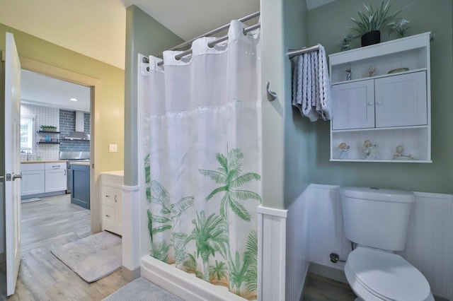 bathroom with backsplash, curtained shower, wood finished floors, vanity, and toilet