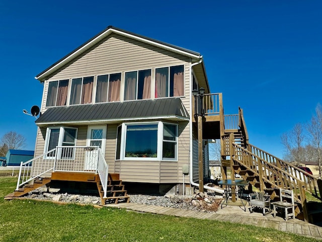 back of property featuring stairway, a lawn, and a sunroom
