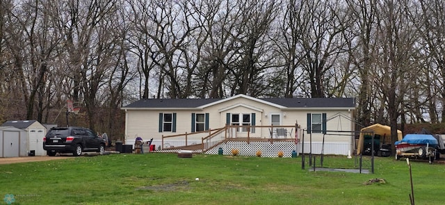 manufactured / mobile home featuring a storage shed, an outbuilding, a front yard, and a wooden deck