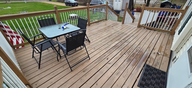 wooden deck featuring a lawn and outdoor dining space