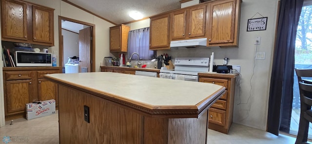 kitchen with a kitchen island, brown cabinets, light countertops, under cabinet range hood, and white appliances