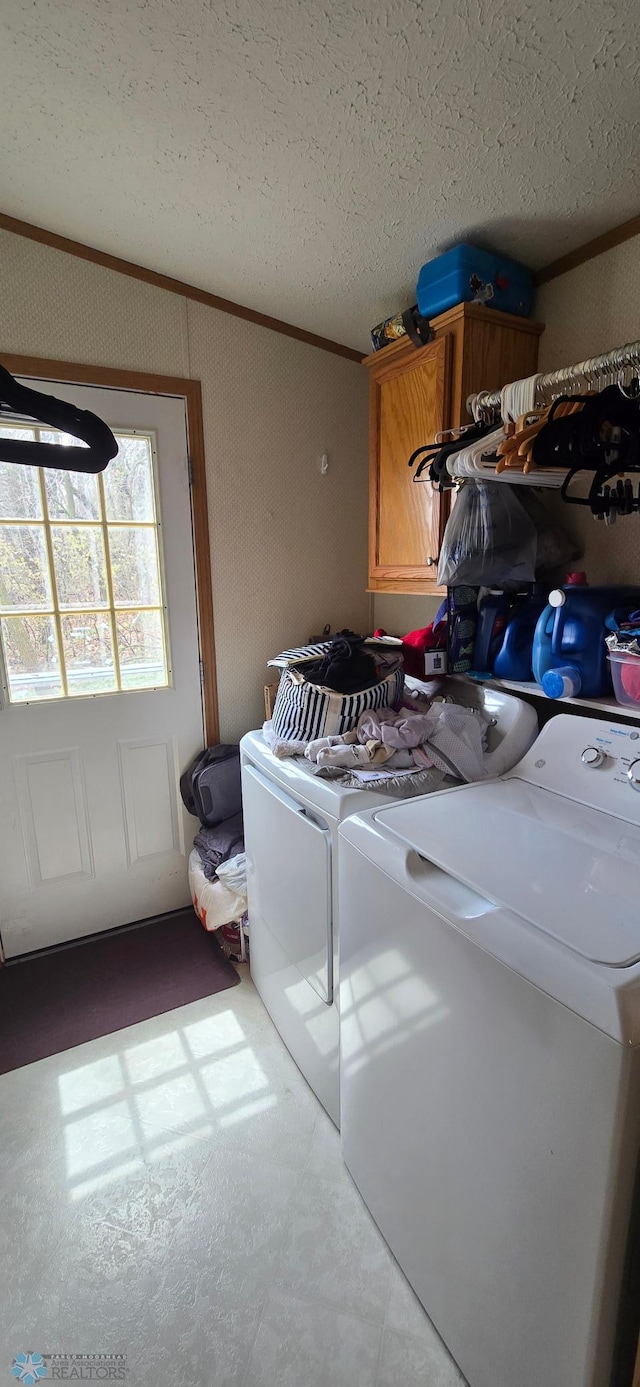 washroom with cabinet space, independent washer and dryer, a textured ceiling, and crown molding
