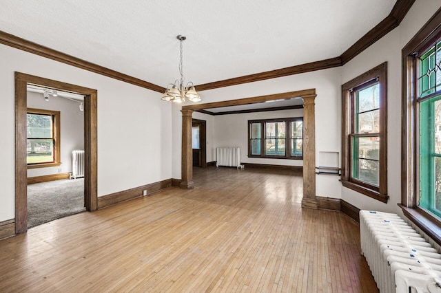 spare room featuring decorative columns and radiator heating unit