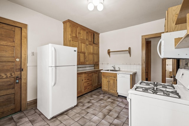 kitchen featuring open shelves, white appliances, light countertops, brown cabinets, and a sink