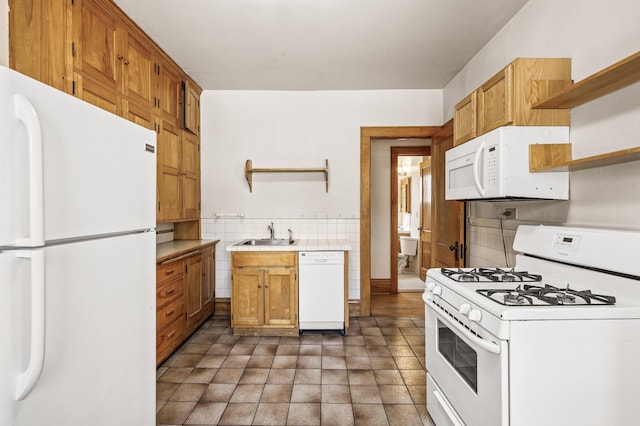 kitchen with tile walls, open shelves, a sink, tile counters, and white appliances