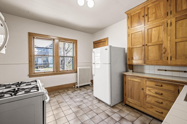 kitchen with white appliances, tile counters, brown cabinets, and radiator heating unit