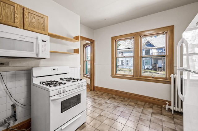 kitchen featuring open shelves, light tile patterned floors, baseboards, radiator heating unit, and white appliances