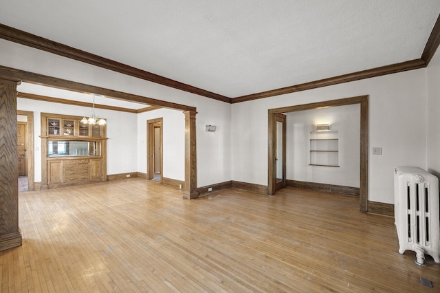 unfurnished room featuring radiator, ornamental molding, light wood-type flooring, and a chandelier