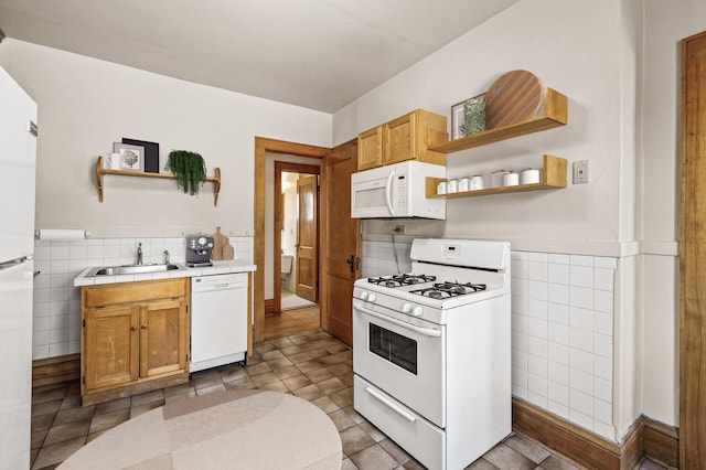 kitchen with white appliances, open shelves, tile walls, and a sink