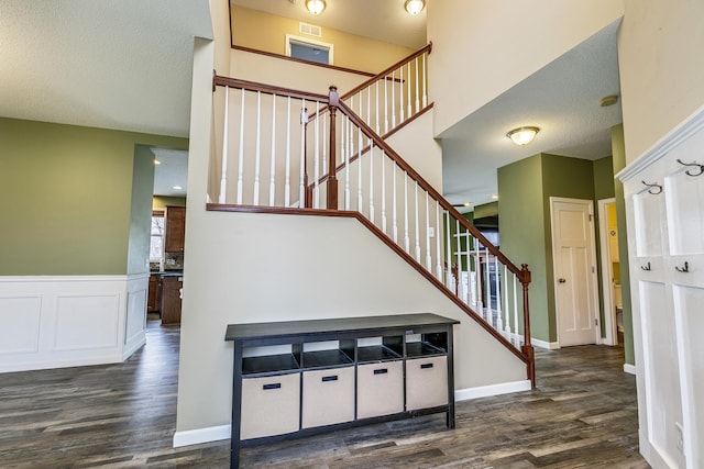 stairway featuring a wainscoted wall, wood finished floors, and visible vents