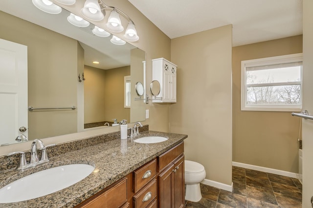 bathroom with baseboards, a sink, stone finish floor, and toilet