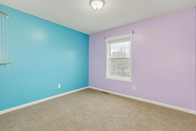 carpeted spare room featuring baseboards, a textured ceiling, and visible vents