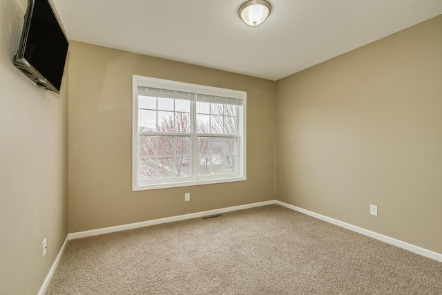 empty room with carpet flooring, baseboards, and visible vents