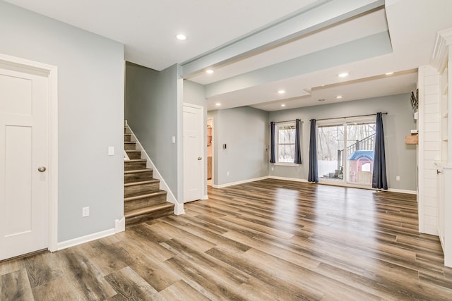 unfurnished living room featuring recessed lighting, baseboards, stairs, and wood finished floors