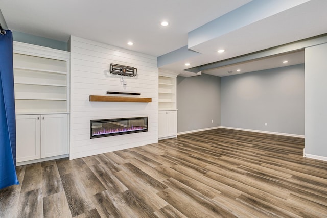 unfurnished living room with recessed lighting, baseboards, wood finished floors, and a fireplace