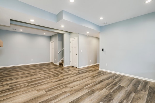 finished below grade area featuring stairway, recessed lighting, and wood finished floors