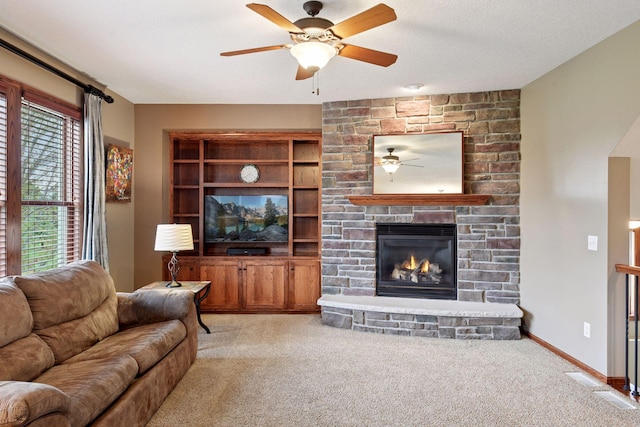 carpeted living area with a fireplace and a ceiling fan