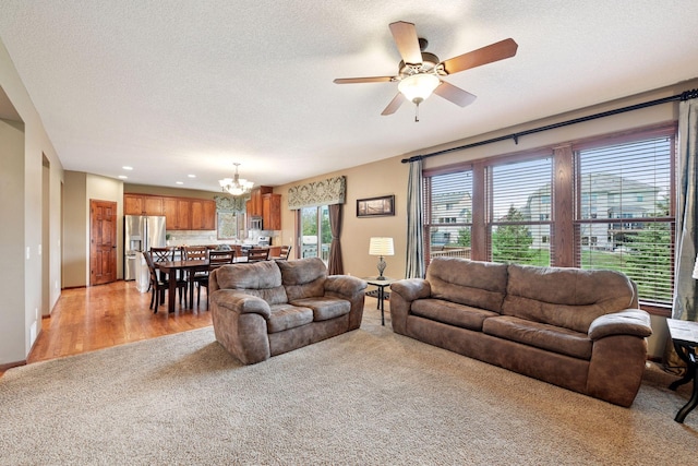 living room with light colored carpet, recessed lighting, a textured ceiling, and ceiling fan with notable chandelier