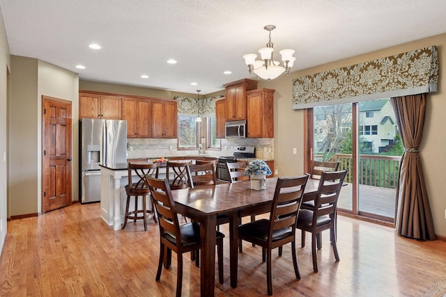 dining area featuring plenty of natural light, recessed lighting, light wood-style flooring, and a notable chandelier