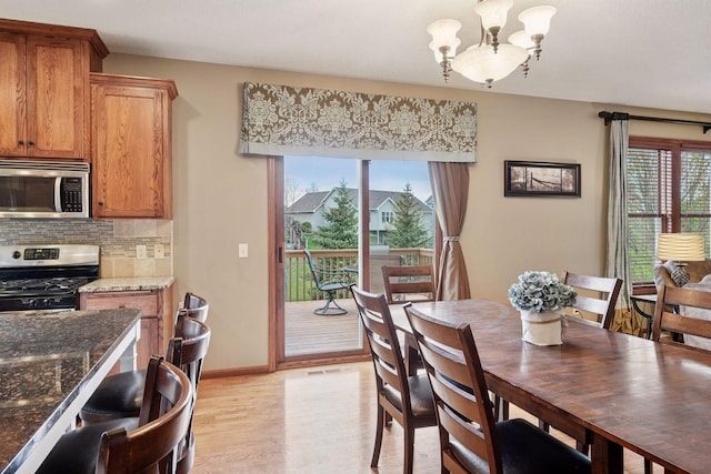 dining space with an inviting chandelier, light wood-style floors, and baseboards