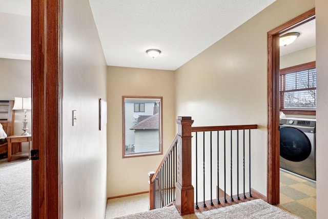 corridor featuring washer / dryer, baseboards, carpet flooring, and an upstairs landing