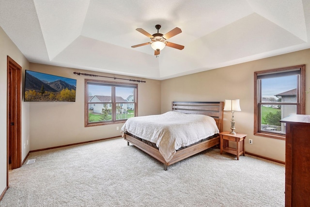 carpeted bedroom with baseboards, a ceiling fan, a tray ceiling, and visible vents