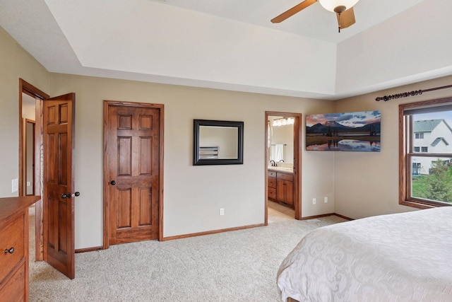 bedroom with baseboards, light carpet, a ceiling fan, and connected bathroom
