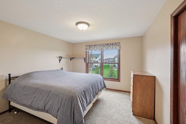 bedroom with baseboards, a textured ceiling, and light colored carpet