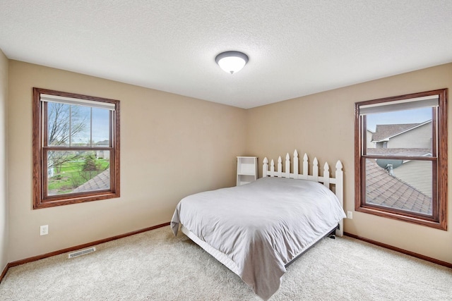 carpeted bedroom featuring a textured ceiling, baseboards, and visible vents
