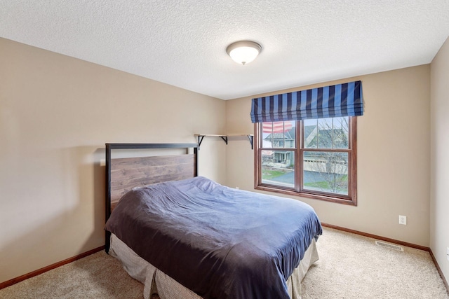 bedroom featuring carpet flooring, a textured ceiling, baseboards, and visible vents