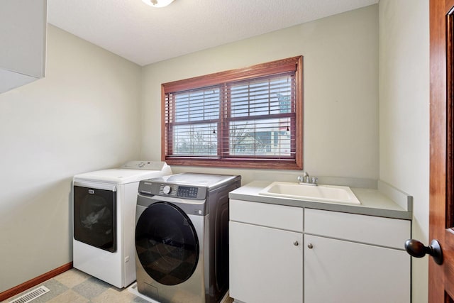 laundry room featuring visible vents, washing machine and clothes dryer, cabinet space, a sink, and baseboards