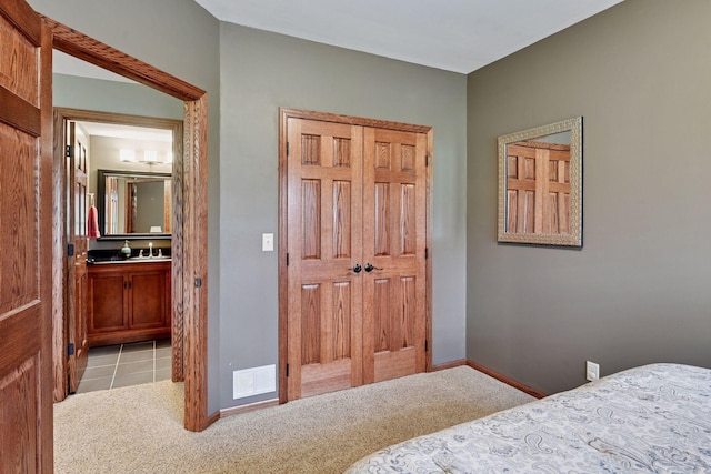 bedroom featuring baseboards, light colored carpet, connected bathroom, and visible vents