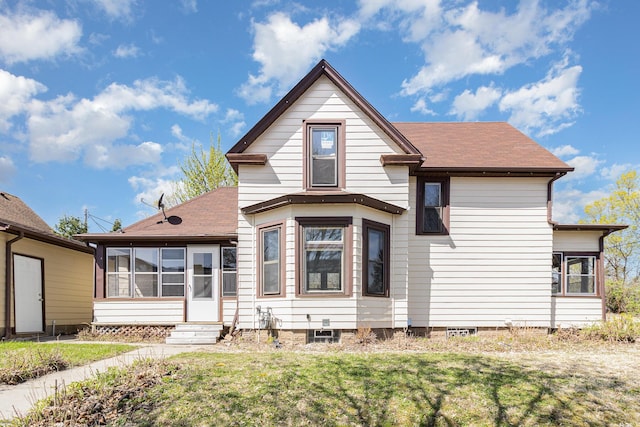 view of front of property with entry steps, a shingled roof, a sunroom, and a front lawn