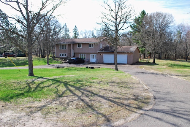 split foyer home with a garage, driveway, and a front lawn