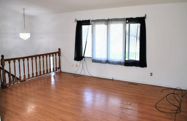 unfurnished room featuring baseboards, visible vents, and wood finished floors