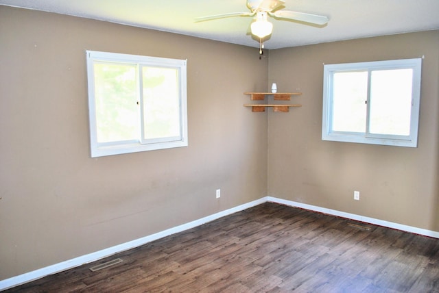 empty room with a ceiling fan, baseboards, visible vents, and dark wood-type flooring