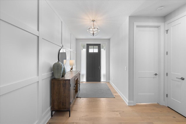 entryway featuring baseboards, an inviting chandelier, and light wood-style flooring