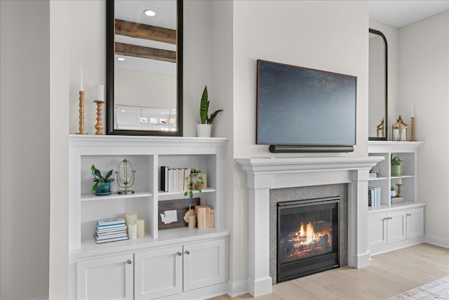 living area with baseboards, wood finished floors, and a tile fireplace