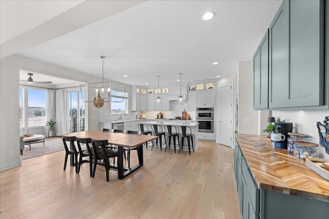 dining area featuring a healthy amount of sunlight, recessed lighting, an inviting chandelier, and light wood-type flooring