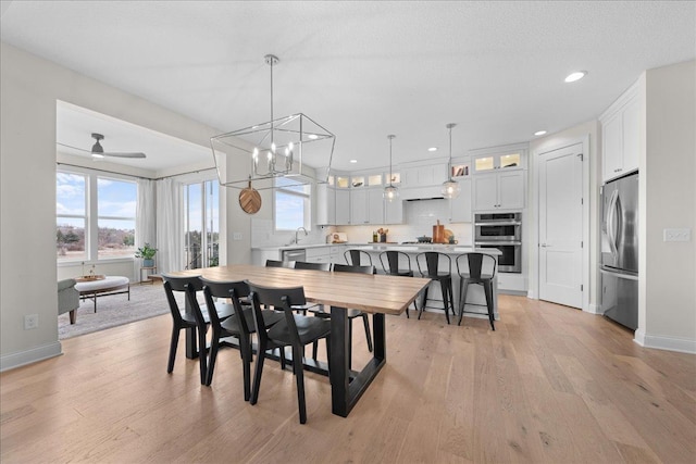 dining room featuring light wood-type flooring, recessed lighting, baseboards, and ceiling fan with notable chandelier