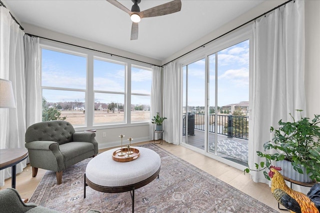 living area featuring a water view, ceiling fan, baseboards, and light wood finished floors