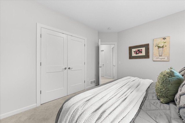 bedroom featuring baseboards, visible vents, a closet, and light colored carpet