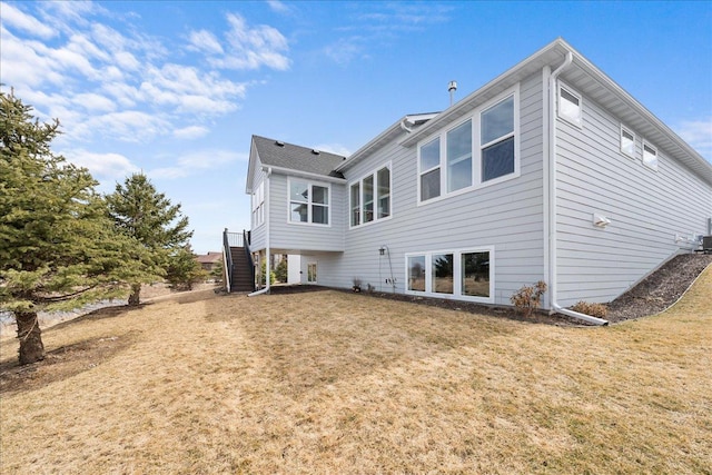 back of property featuring a lawn and stairway