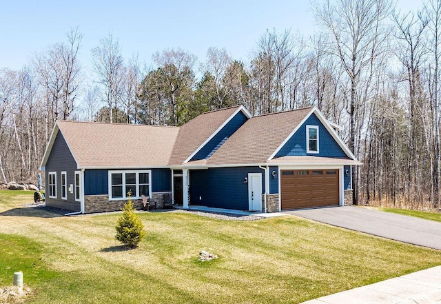 craftsman-style home featuring roof with shingles, a front yard, driveway, and stone siding