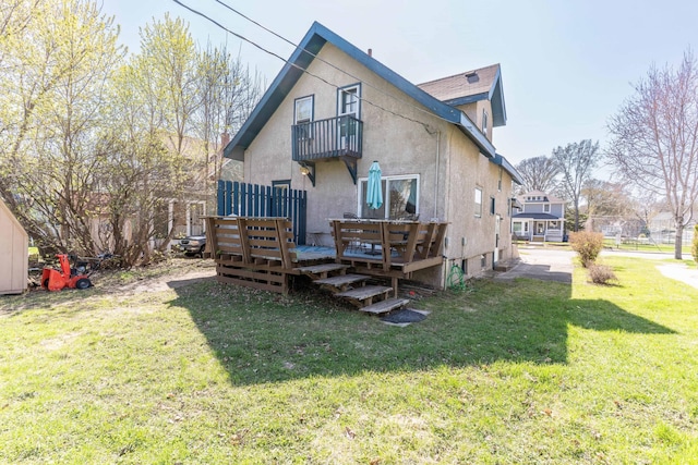 312 Vine St, Fergus Falls, MN 56537 - back of house with a balcony, a wooden deck, stucco siding, and a lawn