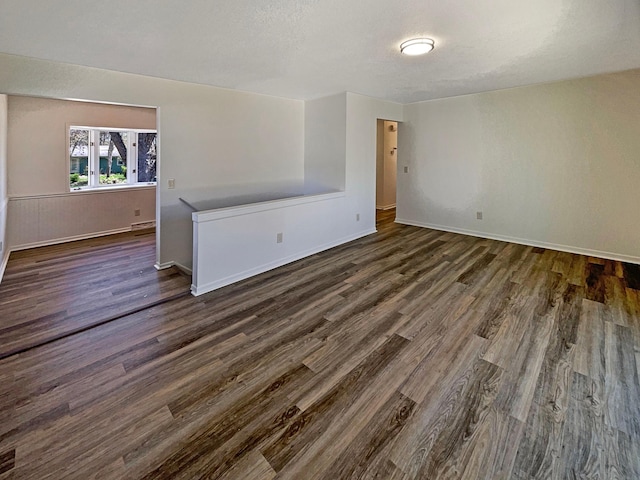 empty room featuring baseboards and dark wood-type flooring