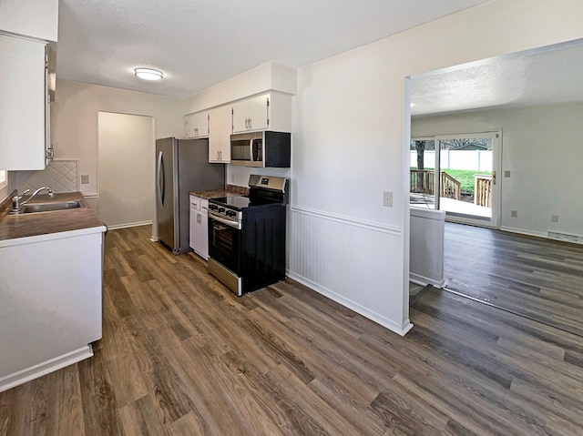 kitchen featuring a sink, stainless steel appliances, white cabinetry, visible vents, and dark wood-style floors