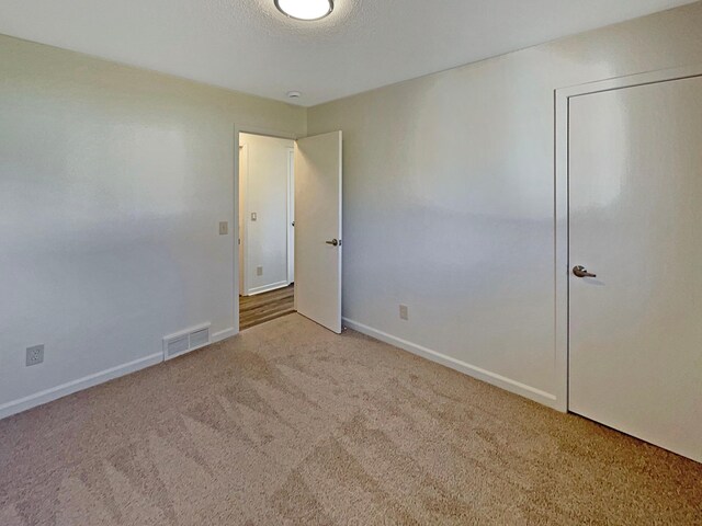carpeted empty room featuring baseboards and visible vents
