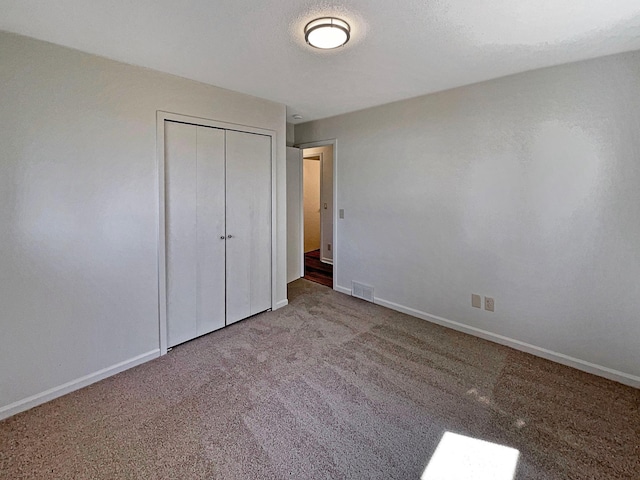 unfurnished bedroom featuring carpet floors, baseboards, a closet, and visible vents